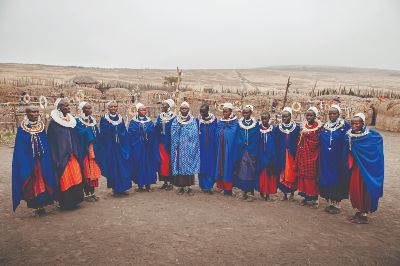 Group of African Masai or Maasai tribe women in blue cloth wearing headpiece and stone beads ornaments. Ethnic group of Ngorongoro Consevation, Serengeti Savanna