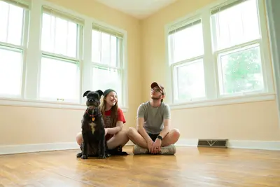 Young couple and their dog sit on the floor of a new home - How to Feel Confident in Your Next Home Decision