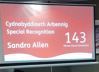 A projected certificate of special recognition for Sandra Allen having achieved 143 whole blood donations