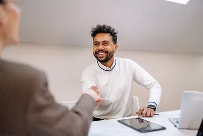 Man grinning as he shakes hands over a business deal – How to Make Real Estate Work for You