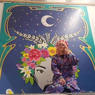 Sophie Jacobsen kneeling in front of her mural