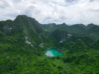 a turquoise lagoon nestled within lush, green limestone mountains in Ninh Bình, Vietnam - Breathtaking Places Every Nature Love