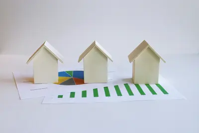 image of three houses sitting on graphs and charts - How Savvy Investors Reduce Property Tax Burdens