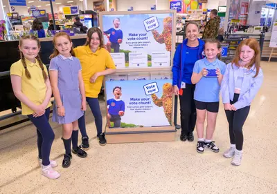 Kids pose with Tesco Wrexham staff as part of the blue token initiative - Vote For Wrexham Schools With Tesco Tokens