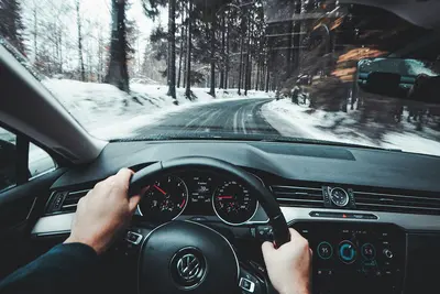 Driver's view from inside a VW, hands on the wheel, speeding down a snowy forest road - Navigating the Roads: Essential Considerations for Vehicle Owners