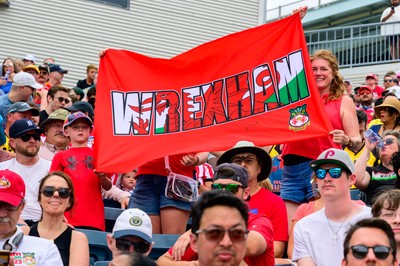 Wrexham supporters hold up a large Wrexham banner in the stands at Subaru Park