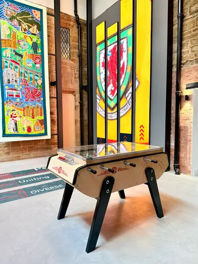 Table football beneath the Football Association of Wales crest in the museum atrium – Football Museum of Wales and Wrexham Museum Opens Its Doors