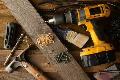 DIY tool kit with cordless drill, hammer, and paintbrush on wooden plank - Your Guide to a Stress-Free Home Makeover