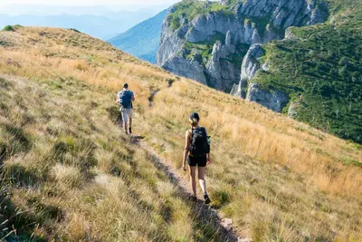 Hikers on mountain ridge trail with cliff views - Why a Walking Holiday Is Your Next Adventure