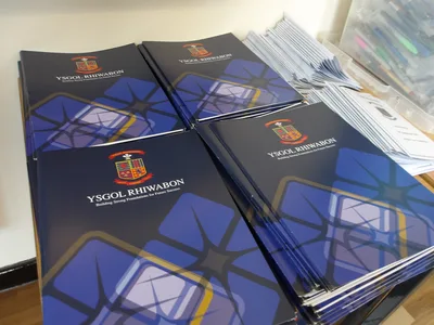Stacks of Ysgol Rhiwabon booklets on a table – Ysgol Rhiwabon Open Evening Welcomes Record Numbers