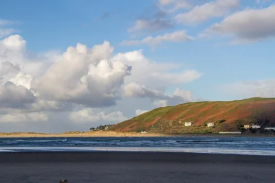 Aberdyfi village beneath green hills across the Dyfi estuary from the beach – The Aberdyfi Guide Review: Six Walks Through Aberdyfi’s Hidden History
