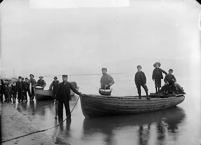 Historic black and white photo of fishermen and boats on the shore at Aberdyfi – The Aberdyfi Guide Review: Six Walks Through Aberdyfi’s Hidden History