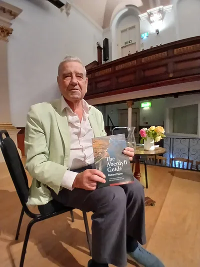 Richard Mayou holding a copy of The Aberdyfi Guide – The Aberdyfi Guide Review: Six Walks Through Aberdyfi’s Hidden History