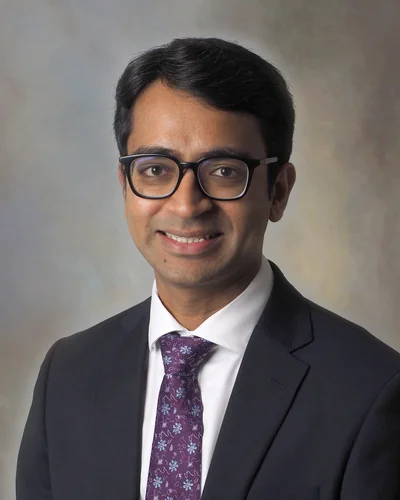 Consultant hand and wrist surgeon Preetham Kodumuri smiling in a suit and tie – New Initiatives for Wrexham University and the Maelor Hospital