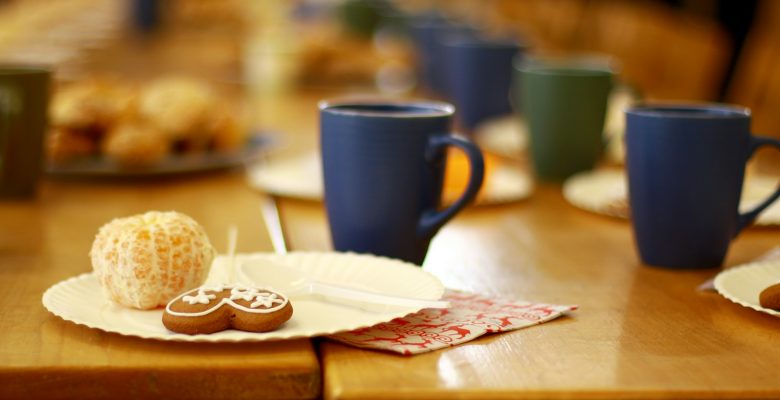 A festive table set with cups of tea, tangerines and homemade biscuits